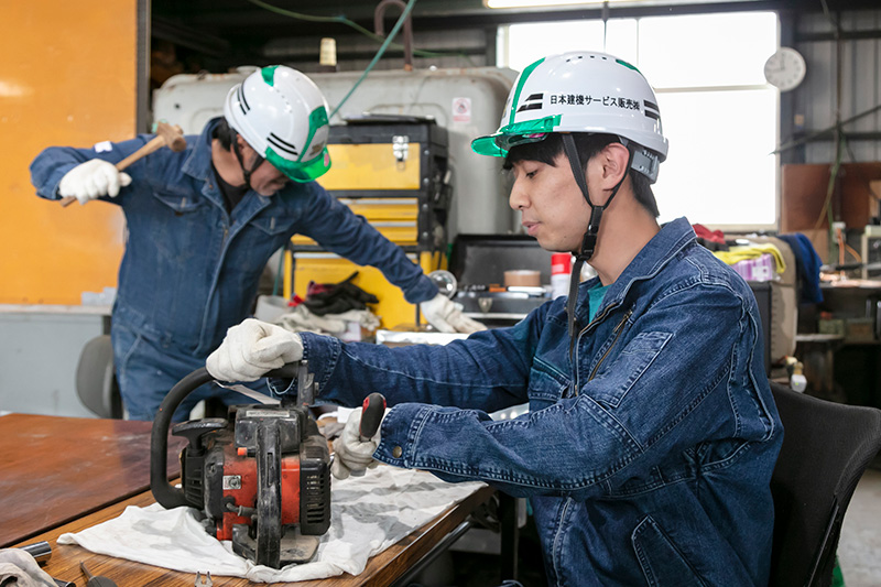 パソコンで書類を確認する社員とヘルメット
